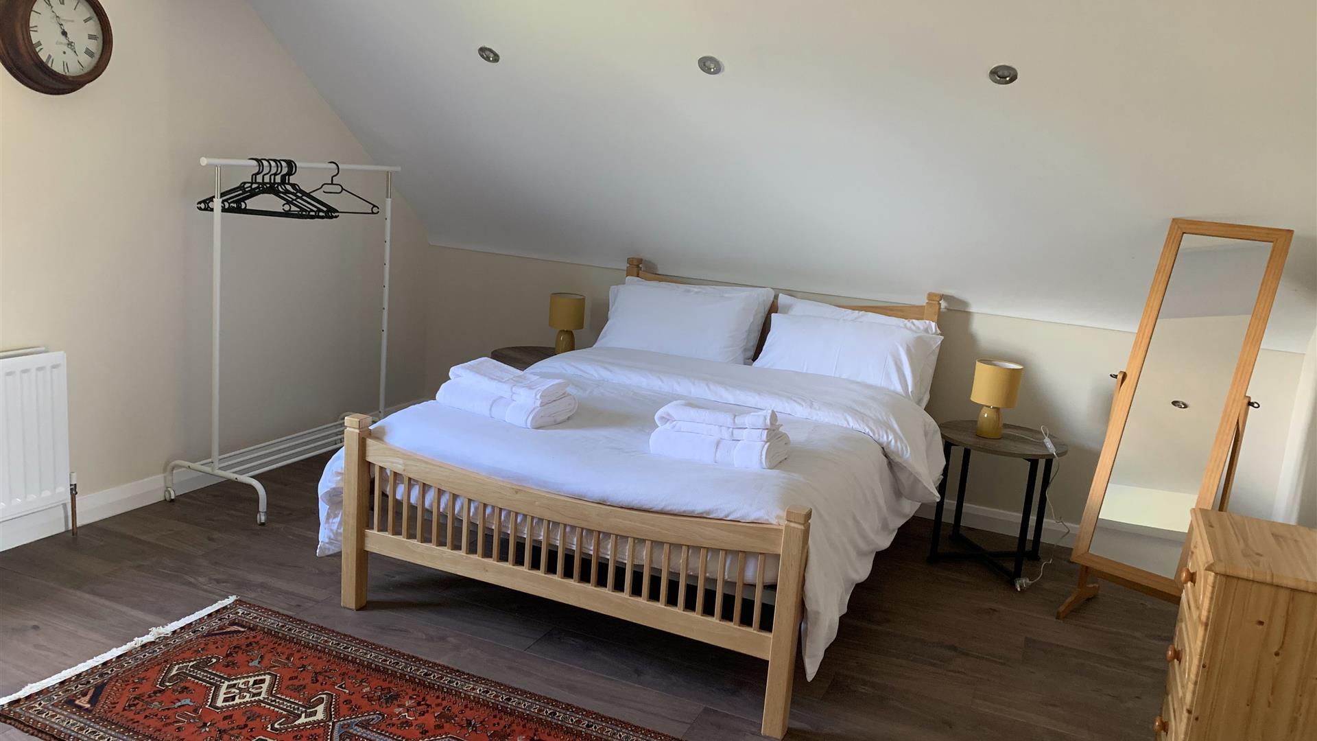 Image shows bedroom in loft with double bed, dressing mirror and clothes rail