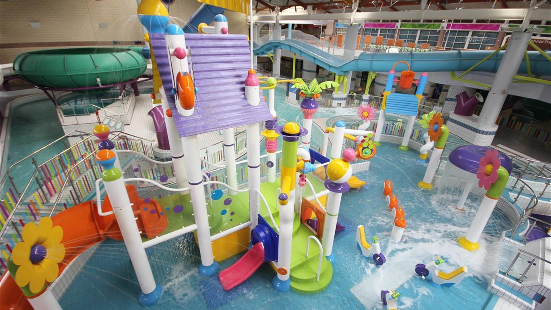 Image shows swimming pool with lots of brightly coloured slides