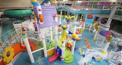 Image shows swimming pool with lots of brightly coloured slides