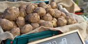 Image shows lots of potatoes resting on a sack on a stall