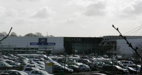 Image is of shop units and car park full of cars