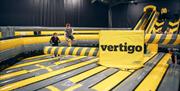 Image is of the large inflatables and children jumping on to them. The word Vertigo is branded on the inflatable.