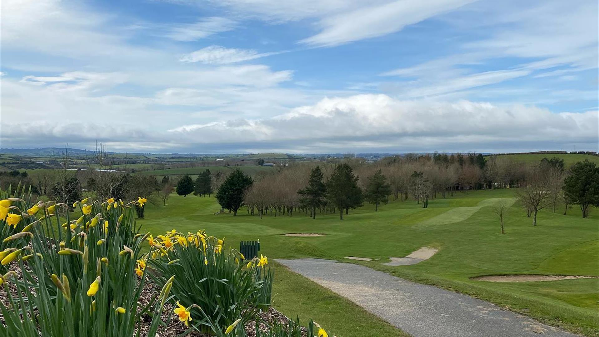 Image shows golf course, walking path and view of countryside beyond