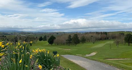 Image shows golf course, walking path and view of countryside beyond