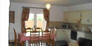 Image shows kitchen area with dining table and 6 chairs looking out patio doors onto garden