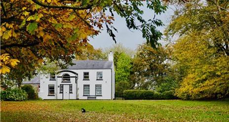 Image is of Ballance House surrounded by trees and Autumn colours