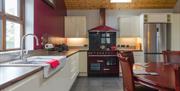 Image shows kitchen and dining area with tiled floor, dining table and chairs, all mod cons
