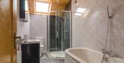 Image shows bath with overhead shower attachment, walk in shower cubicle, toilet and wash basin