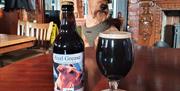 An image of Axel the dog with the latest craft beer of bottle conditioned stout called Axel Grease.