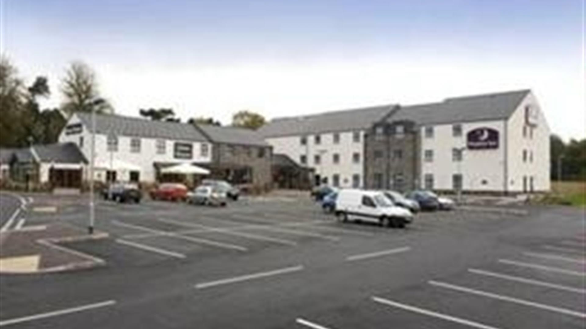 Image shows front of hotel and car parking spaces