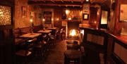 Image shows bar area with open fire lit and low level lighting