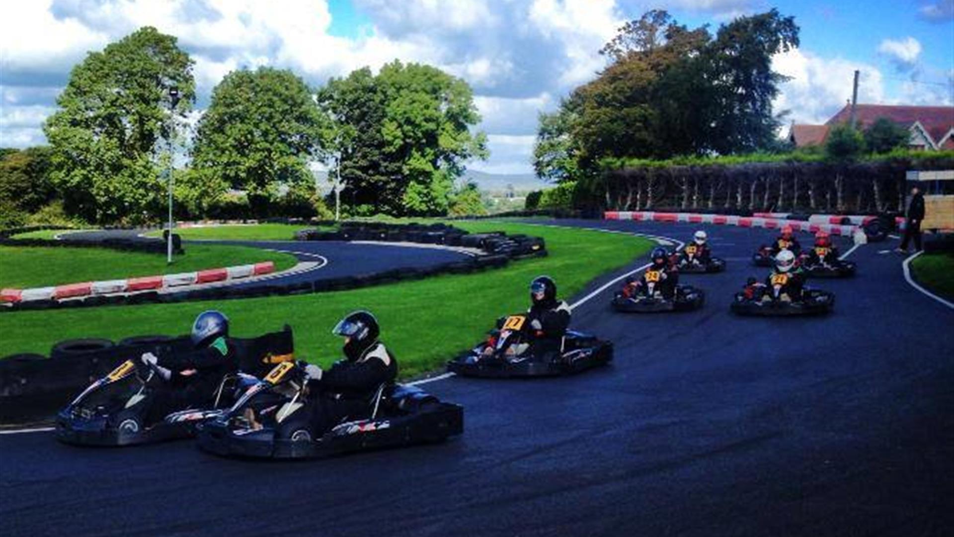 Image is of various people racing go-karts on an outdoor track