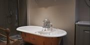 Image is of free standing roll bath, walk in shower and wood floor boards