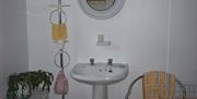 Image shows sink with mirror above plus chair with towel draped over it