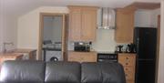 Image shows leather sofa in lounge/dining area plus open doorway to utility room showing washing machine
