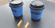 Image shows 2 coffee cups with Caffe Nero branding on table outside premises