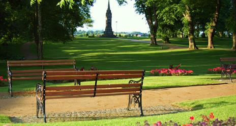 Image is of 2 park benches in the grounds of Castle Gardens in Lisburn