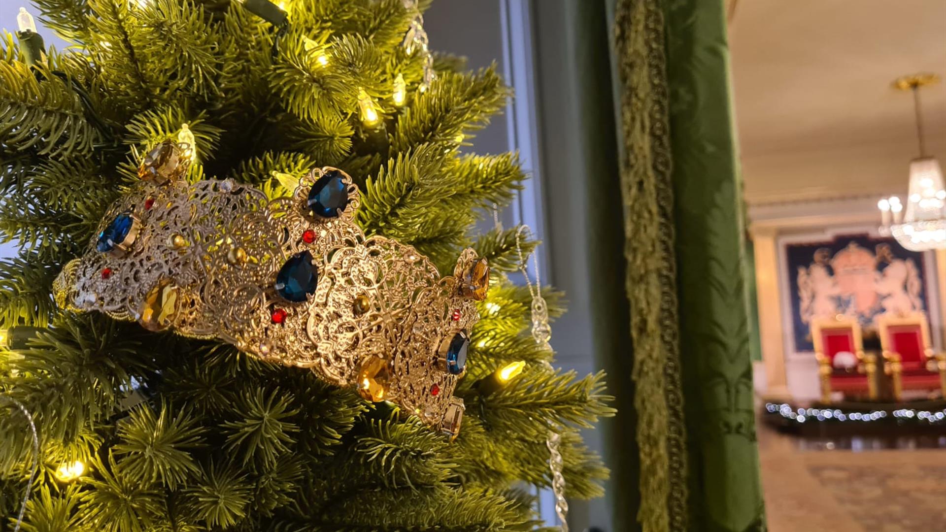 An image of a Christmas tree by the entrance to the Throne Room. The tree has lights and a gold crown with jewels.