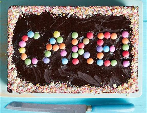 Image is of a cake with sweets spelling CAKE