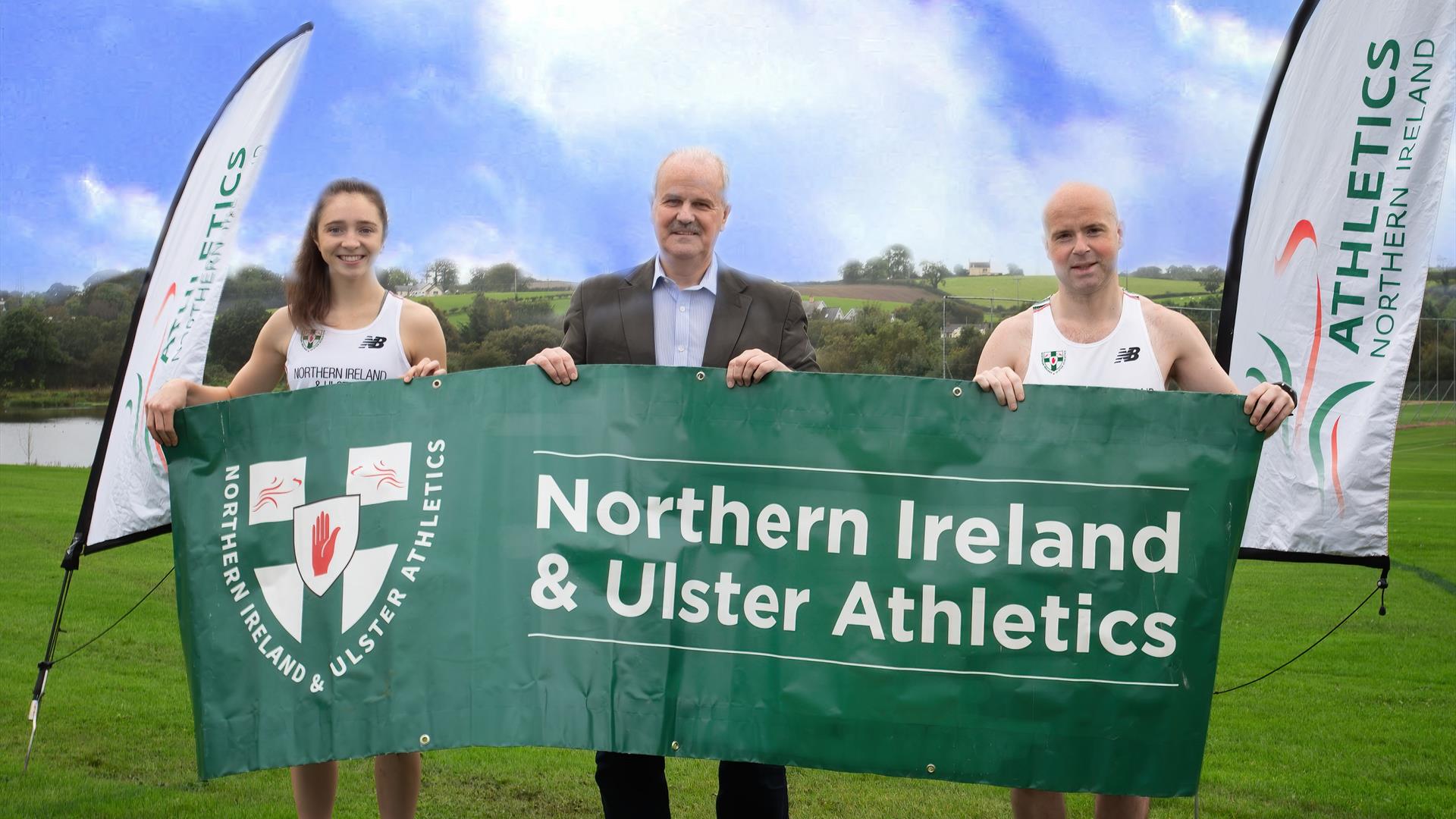 Image is of two runners holding a banner advertising Northern Ireland & Ulster Athletics