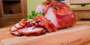 Image is of sliced ham or gammon on a wooden chopping board