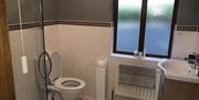 Image shows bathroom with shower, sink and toilet plus large window