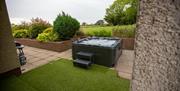 Image shows hot tub in back garden overlooking surrounding fields