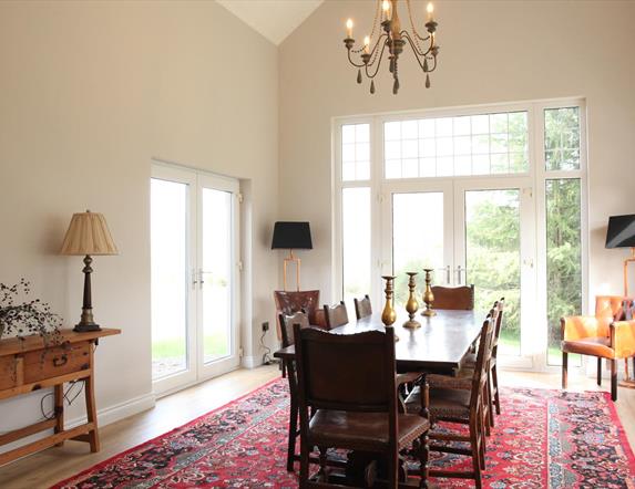 Image shows large dining room with table and 8 chairs. Patio doors onto garden area
