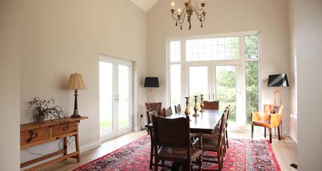 Image shows large dining room with table and 8 chairs. Patio doors onto garden area