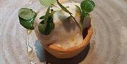 Image is of a Yorkshire pudding with a portion of fish and sauce on top