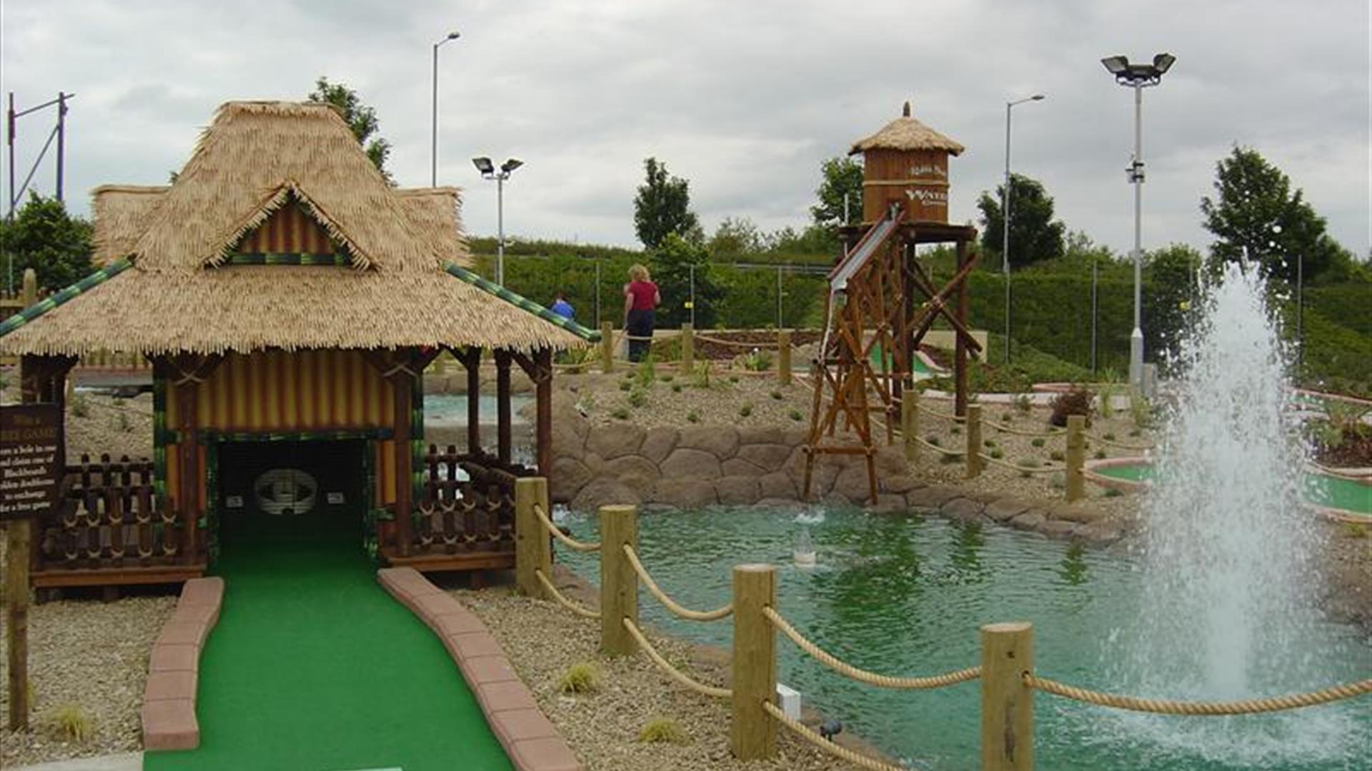 Image shows golf putting area with small lake and fountain