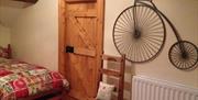 Image shows bedroom with pine door and replica penny farthing bicycle on the wall