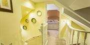 Image shows lemon painted upstairs landing with view of bedroom from open doorway