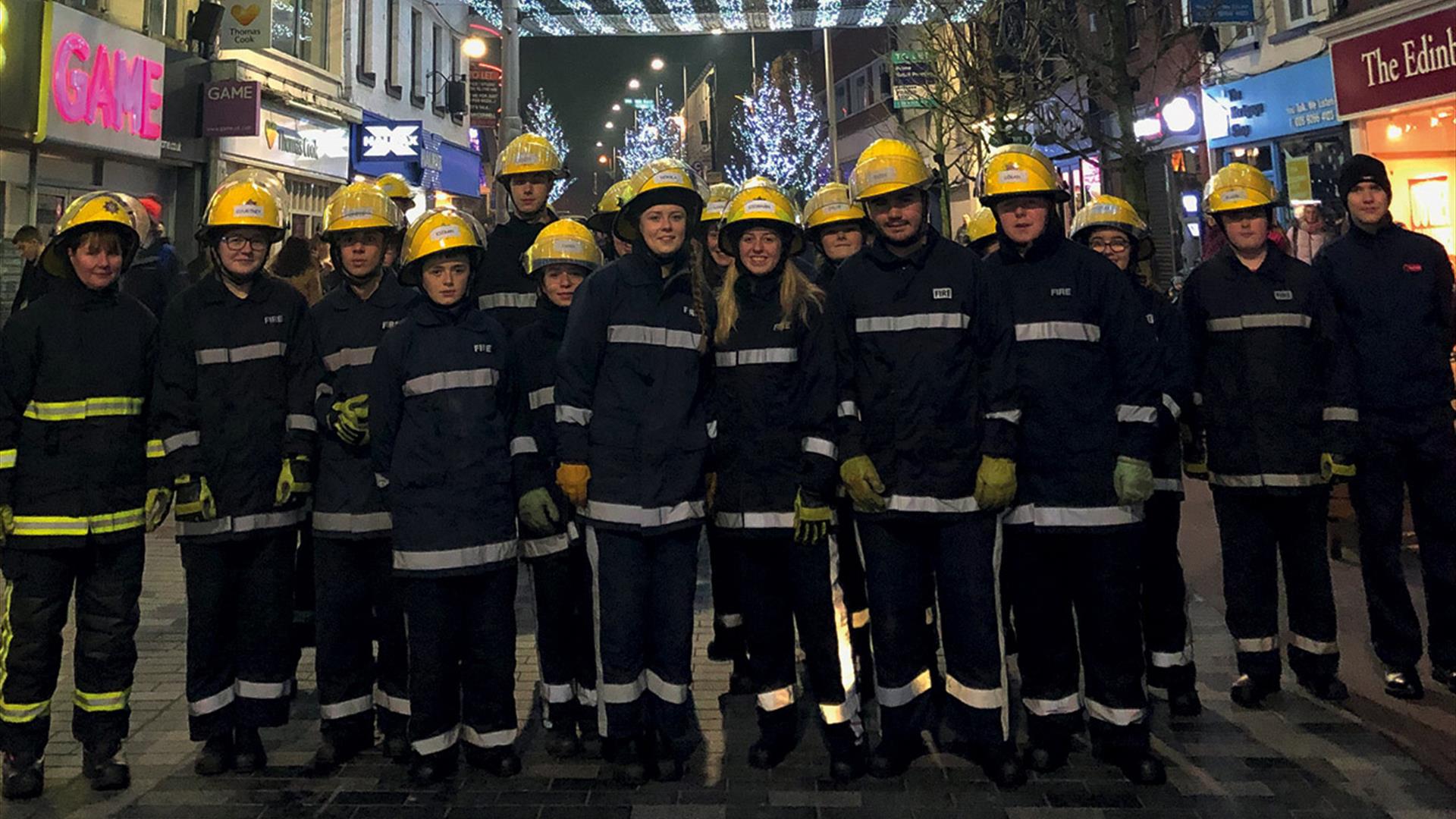 Fire Fighters standing in a row under the Christmas Lights in Bow Street