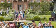 Audience watching a musical performance from striped deckchairs in front of Hillsborough Castle