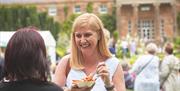 Two women laughing eating pasta in front of Hillsborough Castle