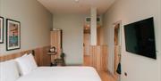 Image is of double bedroom with wooden floor, wardrobe, small desk with chair and TV on the wall