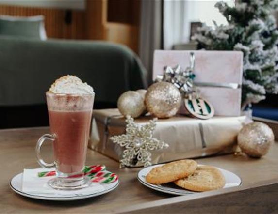 Image shows room in Haslem Hotel with dark green colours with silver wrapped presents and an image of a Christmas latte with peppermint stick and a pl