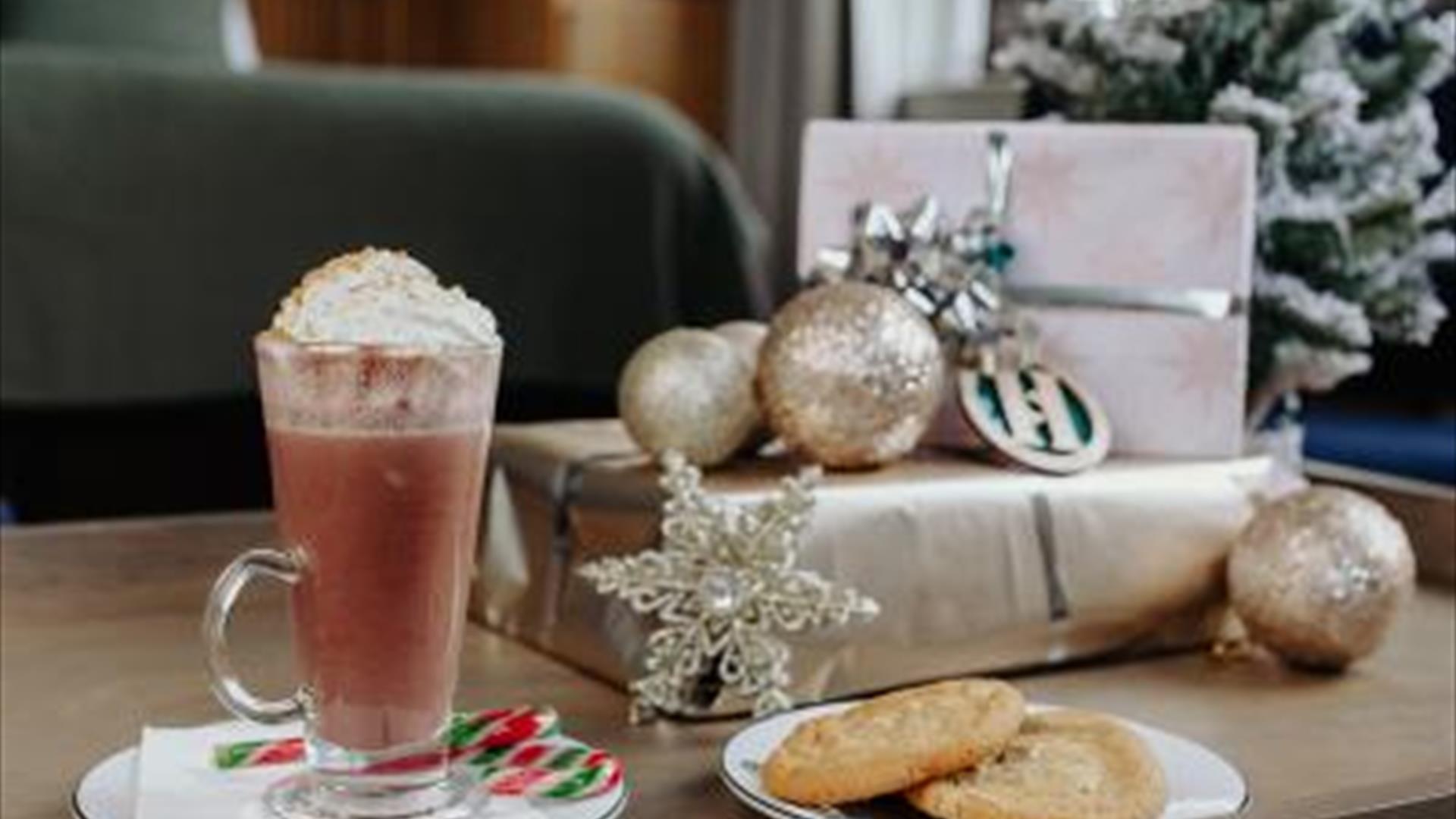 Image shows room in Haslem Hotel with dark green colours with silver wrapped presents and an image of a Christmas latte with peppermint stick and a pl