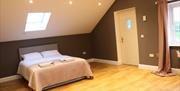 Image shows large double bedroom with wooden floor