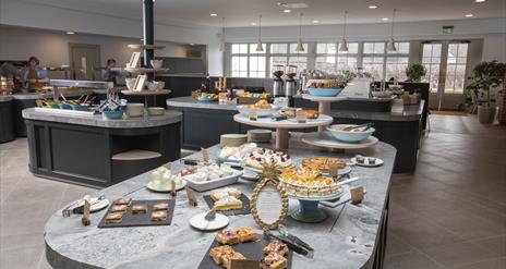 Image shows a creative display of food showing a selection of deserts on a grey marble worktop