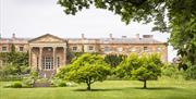 Image is rear of Hillsborough Castle with trees on the lawn
