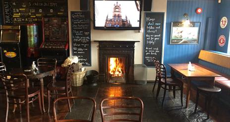 Image is of the lounge area of the bar with open fire blazing and table and chairs