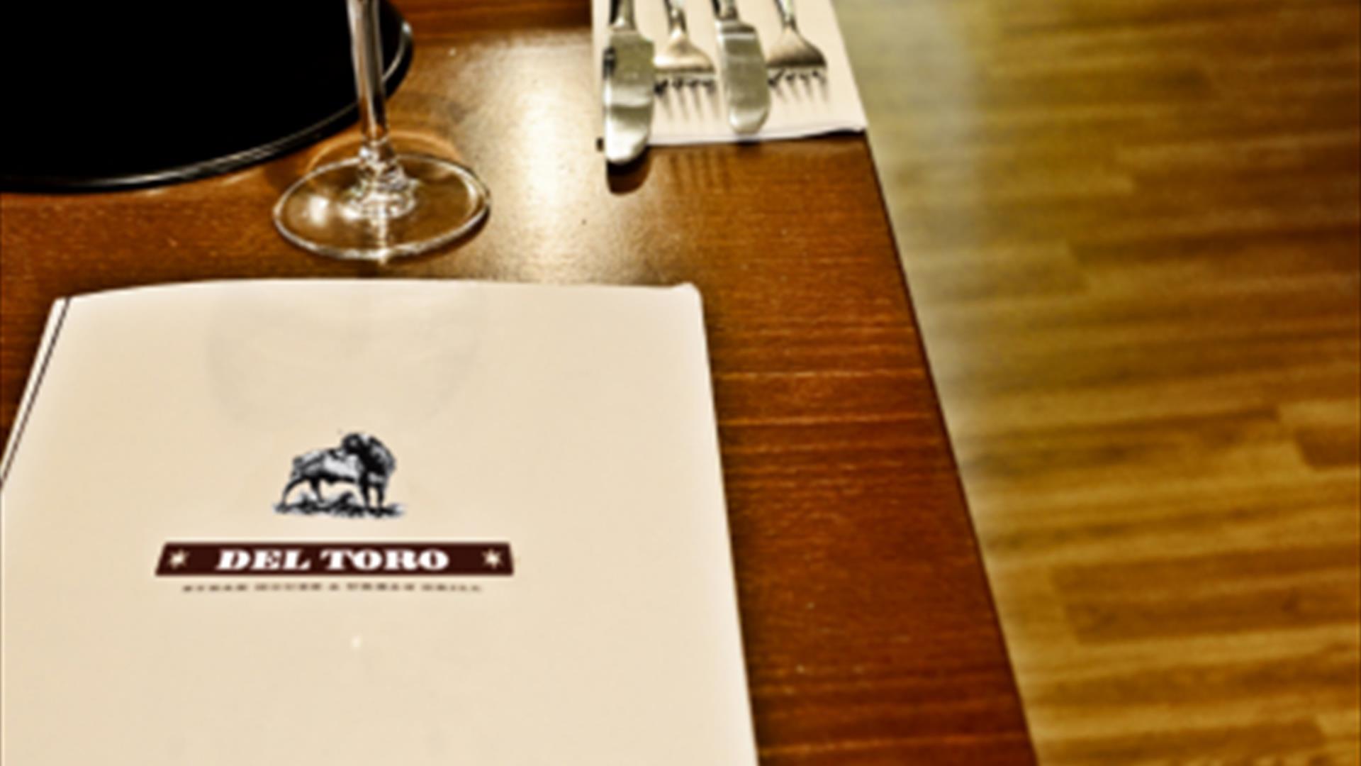 Images shows table laid with cutlery and wine glass with Del Toro restaurant menu also on table