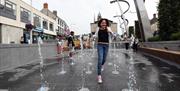 Girl running through fountains in Market Square, Lisburn