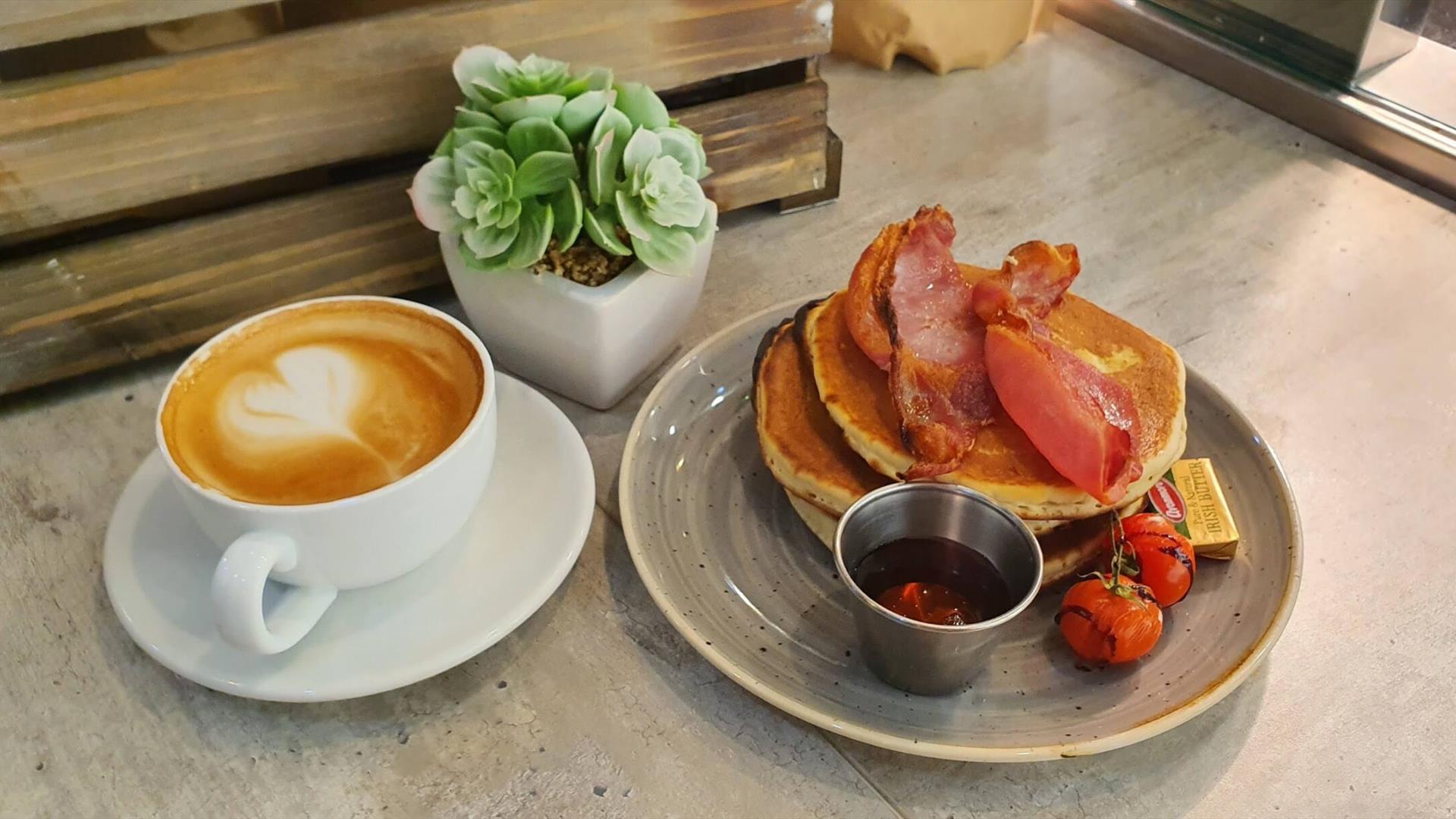 Image shows a cup of coffee and bacon with pancakes at Paul Hampton cafe