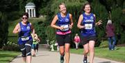 Runners running up the hill in the grounds of Hillsborough   Castle with Lady Alice's temple in the background