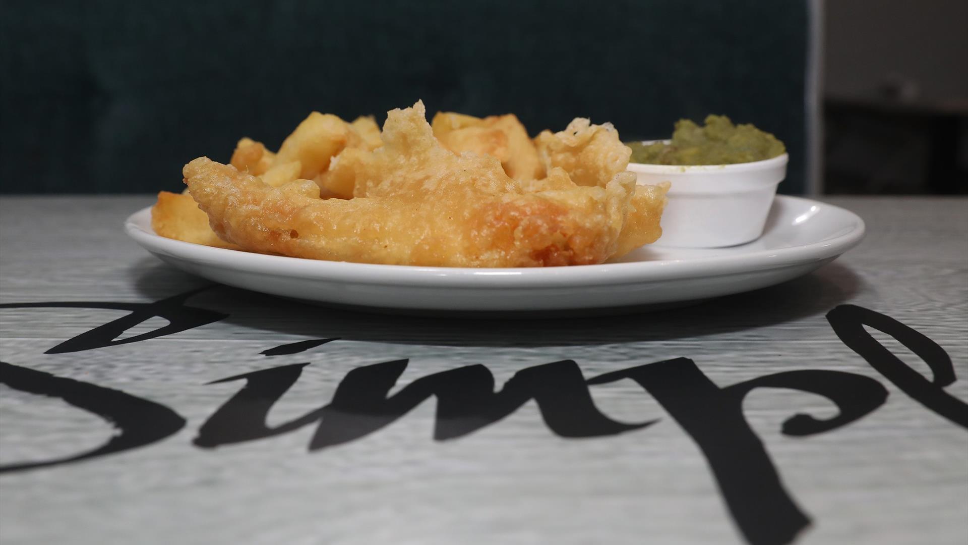 Image is of a plate of fish, chips and mushy peas