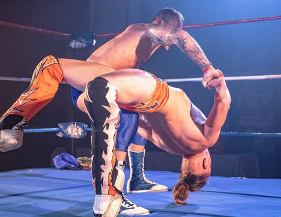 Image is of two wrestlers performing in the ring