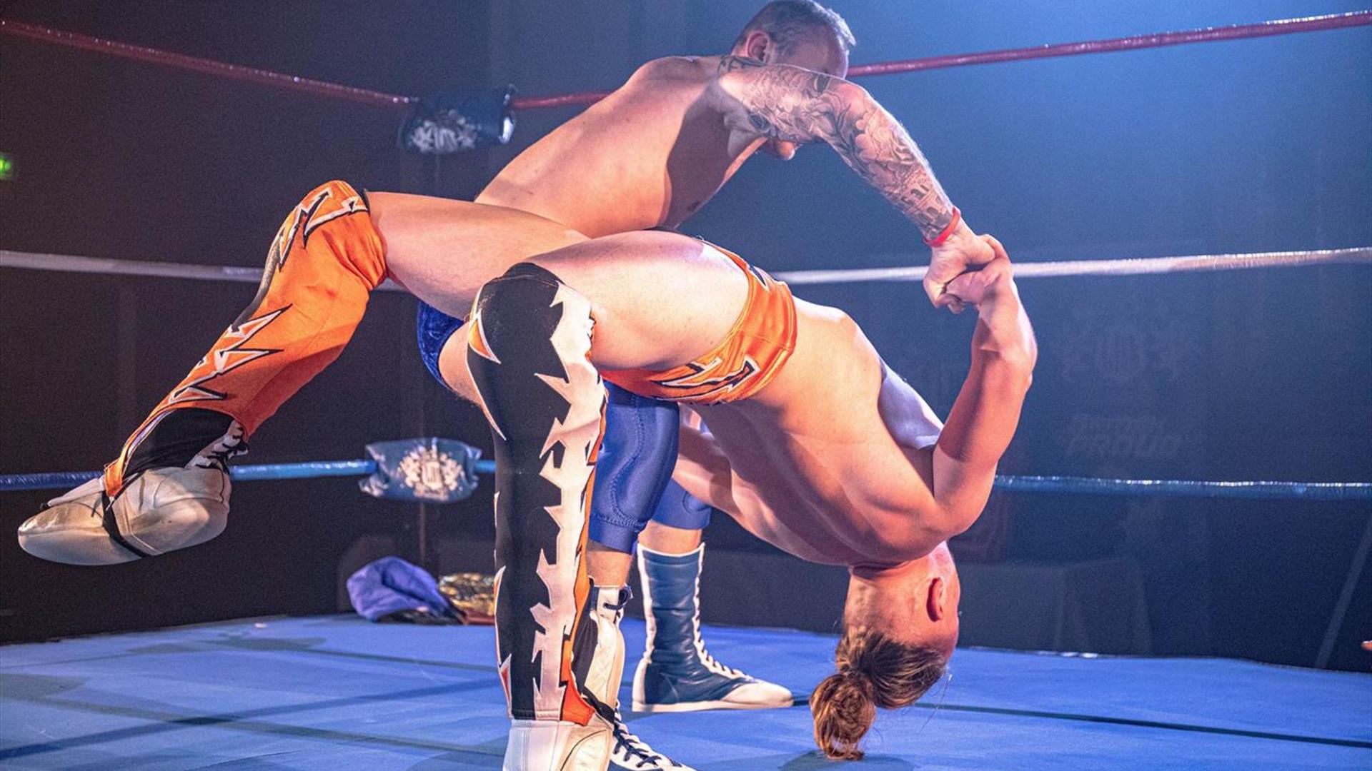 Image is of two wrestlers performing in the ring